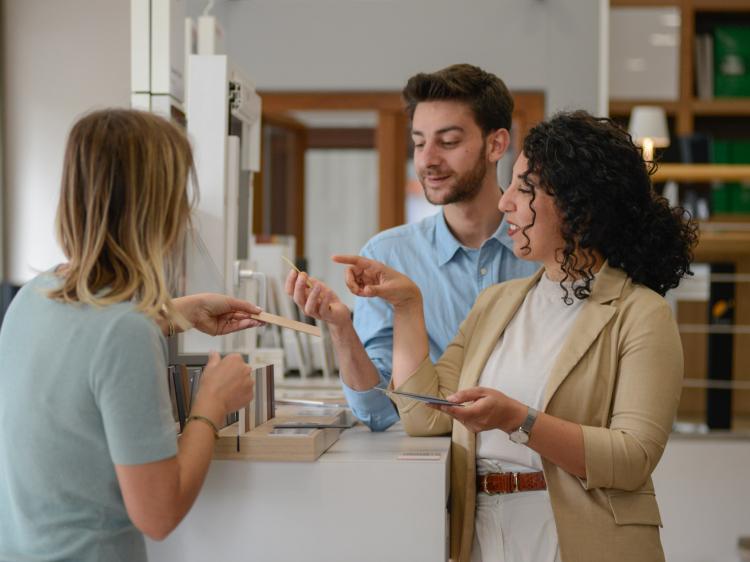 Serena, consulente TuttoPorte, mostra a due clienti un dettaglio tecnico di un serramento in PVC in showroom